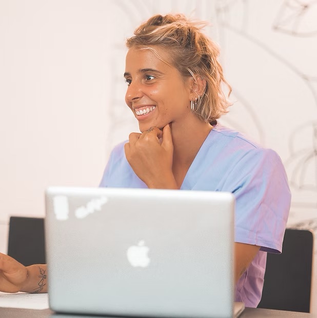 Dottoressa Maimone nutrizionista sorridente alla scrivania davanti al computer portatile durante una consulenza.